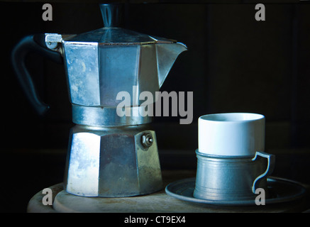 A typical Italian moka coffee maker worn and used and an espresso cup Stock Photo