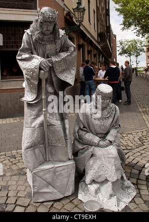 Dusseldorf, Germany - June 9th 2012. Street artists dressed as king and queen, bow to the people crossing by. Stock Photo