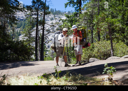 Backpackers consulting a map in the back country, Yosemite National Park, CA, USA Stock Photo