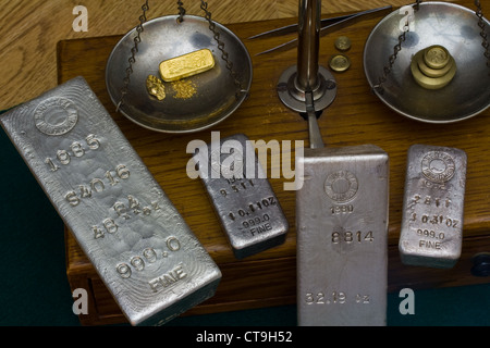 Silver Bullion Bars - Gold Bar, Gold Nugget and Gold Dust on Antique Balance Scale. Brass Weights on Other Side Stock Photo