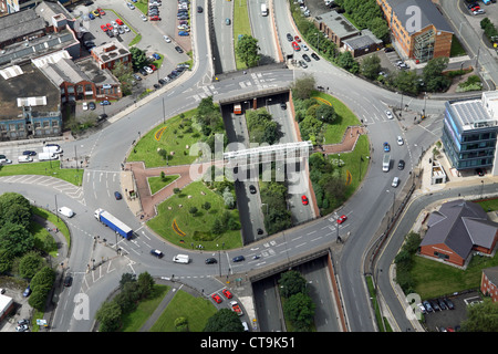 aerial view of a large roundabout over a dual carriageway road with greenery and a footbridge Stock Photo