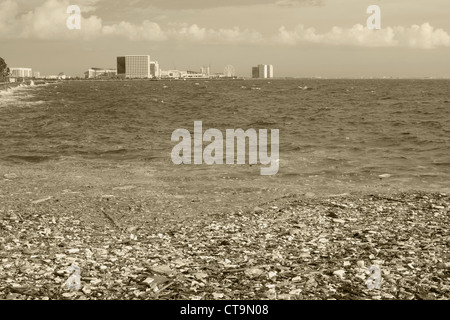 image of a polluted manila bay shore with toxic garbage floating in the foreground and buildings in the background. Stock Photo