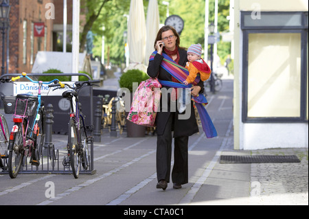 Berufstaetige mother with baby in the street Stock Photo