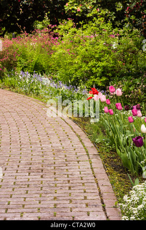 A paved path or walkway through a flower garden Stock Photo