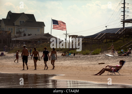 Tourists sunbathing  on Surf City beach , Topsail Island , North Carolina , USA with stars and stripes American flag  summer sun Stock Photo