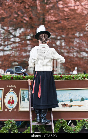 Girl on a ladder wearing traditional costumes, festival of Leonhardiritt, Benediktbeuren, Bavaria, Germany Stock Photo