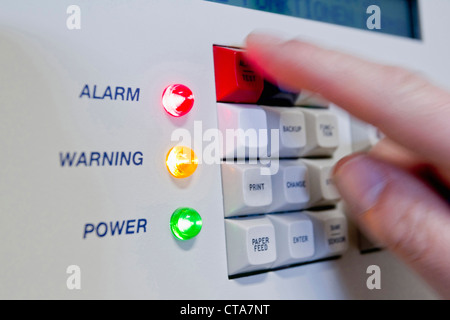 Hand pushing button on alarm system, Germany Stock Photo