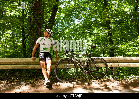 Bicycle racer leaning against guardrail, Bergisches Land, North Rhine-Westphalia, Germany Stock Photo