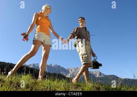 Young couple walking barefoot on the meadow, South Tyrol, Trentino-Alto Adige, Italy Stock Photo