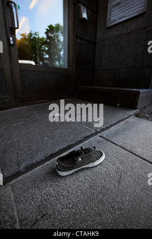 Shoe abandoned in front of the entrance to a building Stock Photo