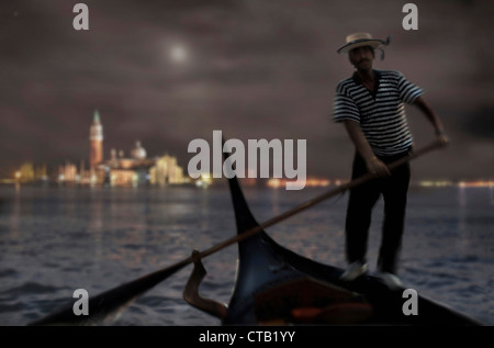 Gondolier wtih gondola at night with a city view in the background, Venice, Italien Stock Photo