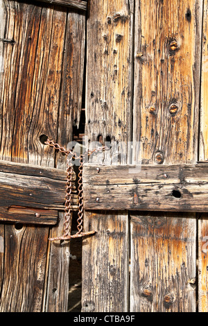 Old wooden door secured with a padlock and iron chain Stock Photo