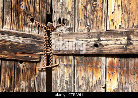 Old wooden door secured with a padlock and iron chain Stock Photo