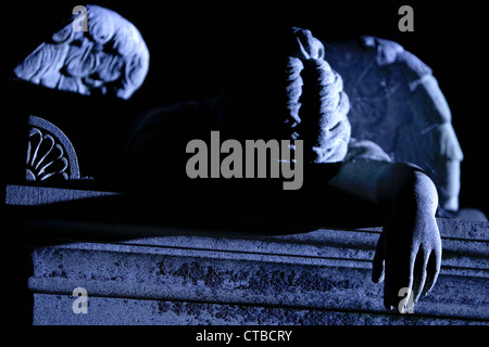 Stone sculpture of a fallen angel on top of a tomb in an historic Southern cemetery in blue moonlight Stock Photo