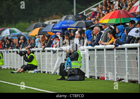Photographers working pitchside getting wet in heavy rain at Maidstone United ground Stock Photo