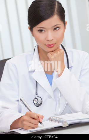 A Chinese Asian female medical doctor writing in a hospital office Stock Photo