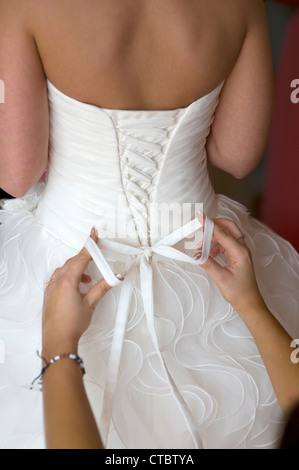 bridesmaid tying the dress  for the bride on her wedding day Stock Photo