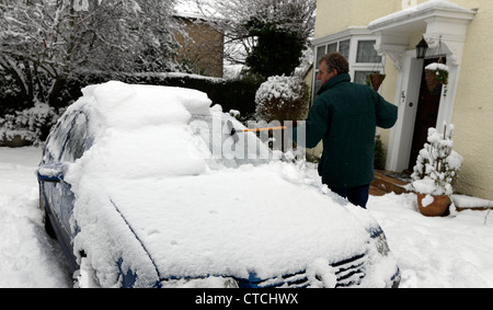 Man Using A Rubber Wonder Broom To Clear The Ice And Snow Off A Car Windscreen During Winter Surrey England Stock Photo