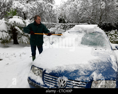 Man Using A Rubber Wonder Broom To Clear The Ice And Snow Off A Car Windscreen During Winter Surrey England Stock Photo