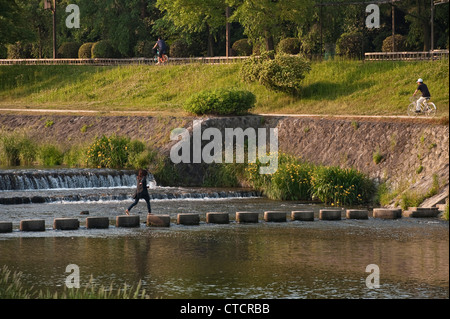 Stepping stones give pedestrians a way to cross the peaceful Kamo River (Kamo-gawa) in central Kyoto, Japan Stock Photo