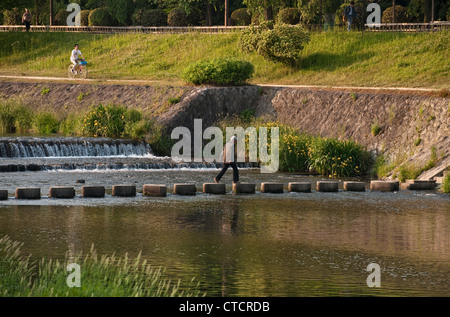 Stepping stones give pedestrians a way to cross the peaceful Kamo River (Kamo-gawa) in central Kyoto, Japan Stock Photo