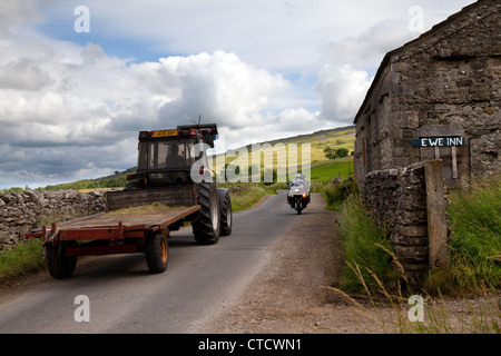 Farm vehicle passing Ewe Inn accommodation Sign; Funny Sign, humorous signs, Comical farmhouse sign near sheep farm in Arncliffe, North Yorkshire Dale Stock Photo