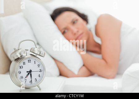 Alarm clock with a woman who just wakes up Stock Photo