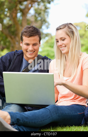 Close-up of young people sitting while using a laptop Stock Photo