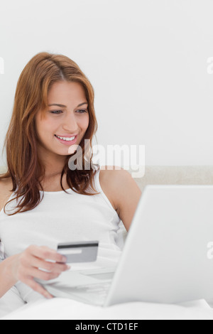 Redheaded sitting on her bed while shopping online Stock Photo