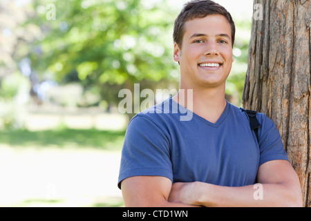 Portrait of a young man leaning against a tree Stock Photo