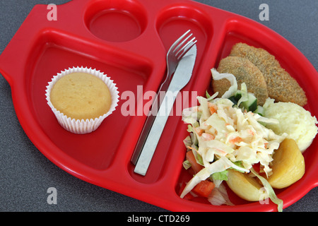 Healthy school lunch dinner served on preformed red plastic tray, salad bean burger, muffin, orange Stock Photo