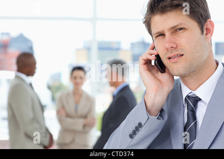 Serious executive looking straight ahead while using a mobile phone Stock Photo