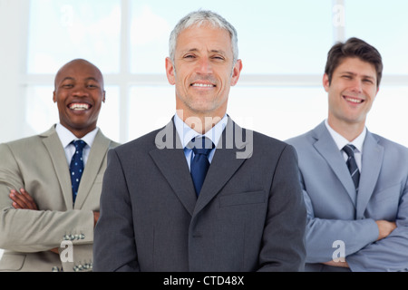 Two young employees standing in the back while laughing and being led by their manager Stock Photo