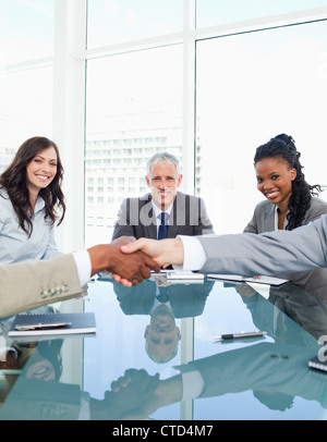 Businesswomen smiling during a meeting while looking at colleagues shaking hands Stock Photo