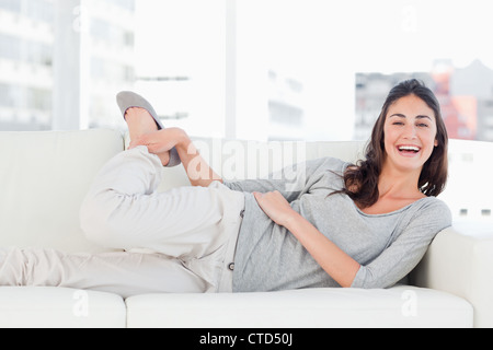 Portrait of a laughing brunette stretching on her sofa Stock Photo