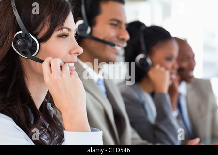 Young businesswoman working with a headset and accompanied by her team Stock Photo