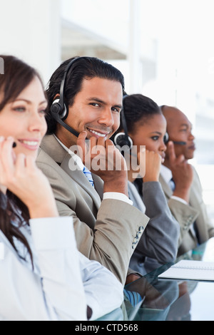 Young smiling call centre worker working among his business team Stock Photo