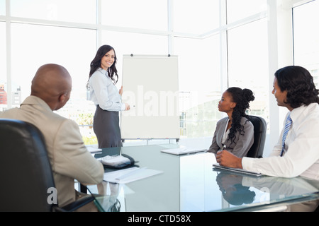 Businesswoman giving a presentation while her co-workers are listening to her Stock Photo