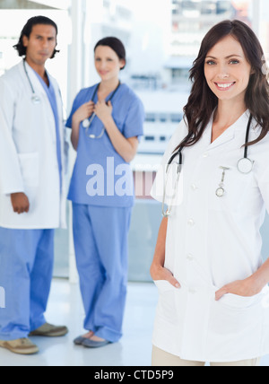 Smiling female doctor standing upright with her hands in her pockets Stock Photo