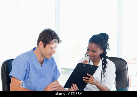 Two nurses working on a professional clipboard in a bright room Stock Photo