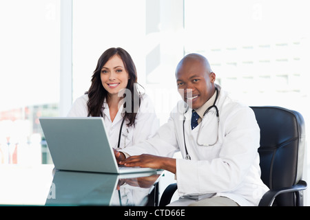 Two nurses working seriously while sitting at the desk in a well lit room Stock Photo