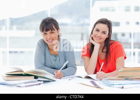 Two smiling students studying together while looking at the camera Stock Photo