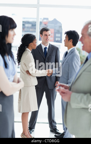 Two executives shaking hands and speaking to another man Stock Photo