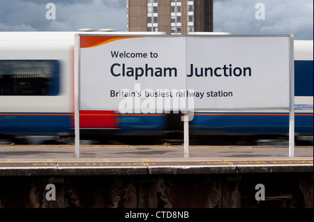 Welcome sign on the platform of Clapham Junction Station, with train blurring past in the background, England. Stock Photo