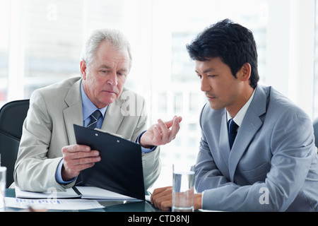Mature businessman giving serious explanations about information on the clipboard to an employee Stock Photo