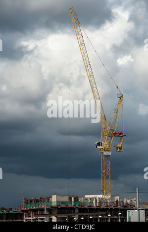 Large yellow crane against a dark grey sky on a construction site in England. Stock Photo