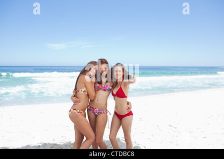 Three friends hold each other in front of the water Stock Photo
