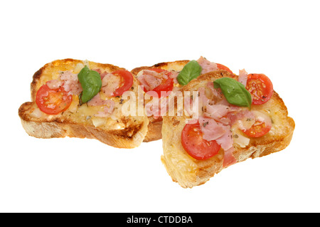 Toasted slices of ciabata bread topped with tomato,onion,cheese and ham with a garnish of basil leaves isolated against white Stock Photo