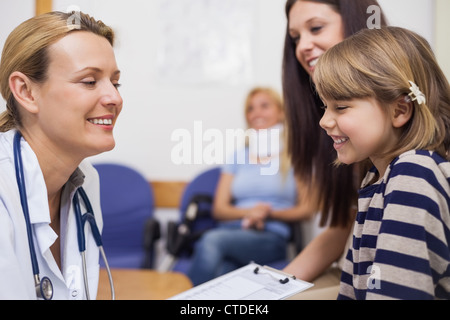 Doctor and girl smiling while sitting in a waiting room Stock Photo