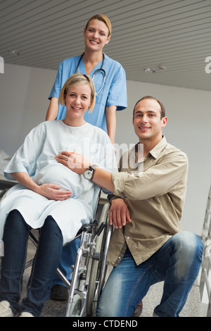 Pregnant woman in a wheelchair with a nurse and a man Stock Photo